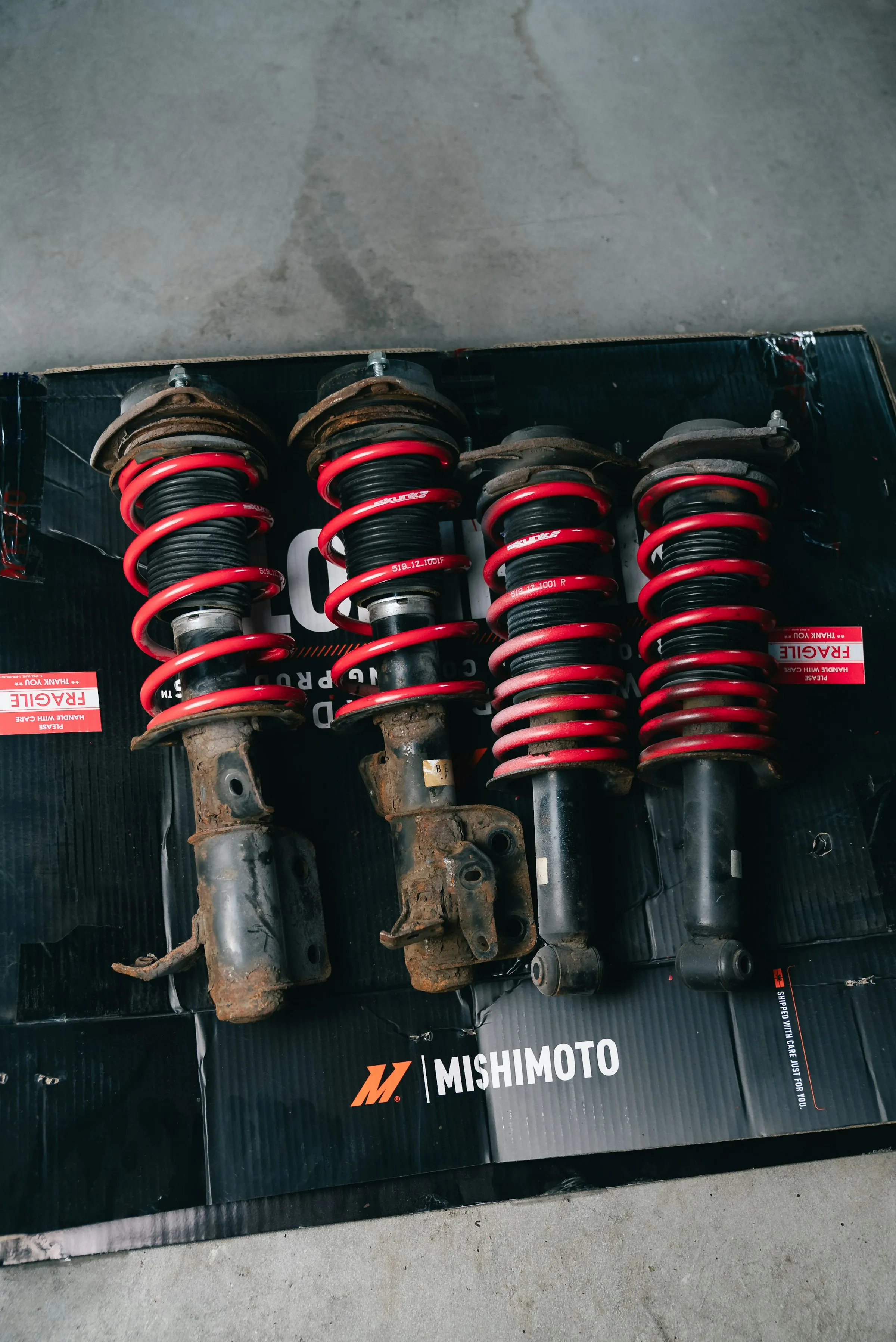 Four car suspension struts with red springs